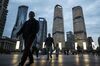 Pedestrians walk past commercial buildings illuminated at dusk in the Lujiazui Financial District in Shanghai, China.