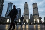 Pedestrians walk past commercial buildings illuminated at dusk in the Lujiazui Financial District in Shanghai, China.