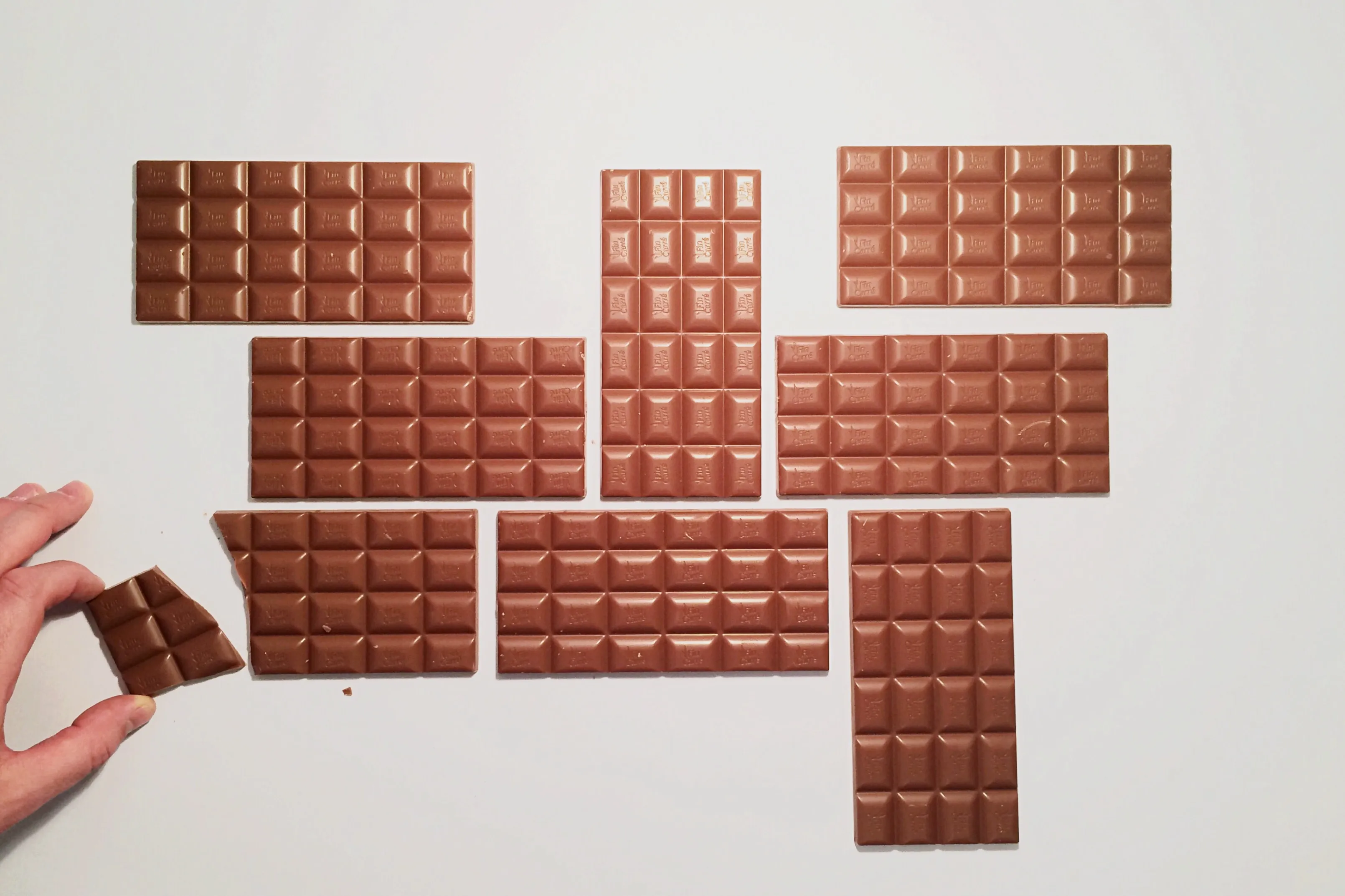 Hand Arranging Chocolate Bars On White Background