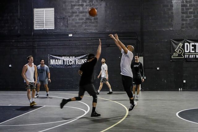 Members of Miami Tech Runs DAO playing basketball on a court .