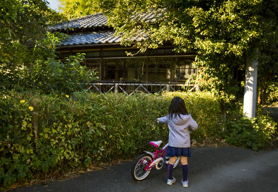 A girl looks at a vacant traditional Japanese wooden house in the town of Kamakura, outside Tokyo.