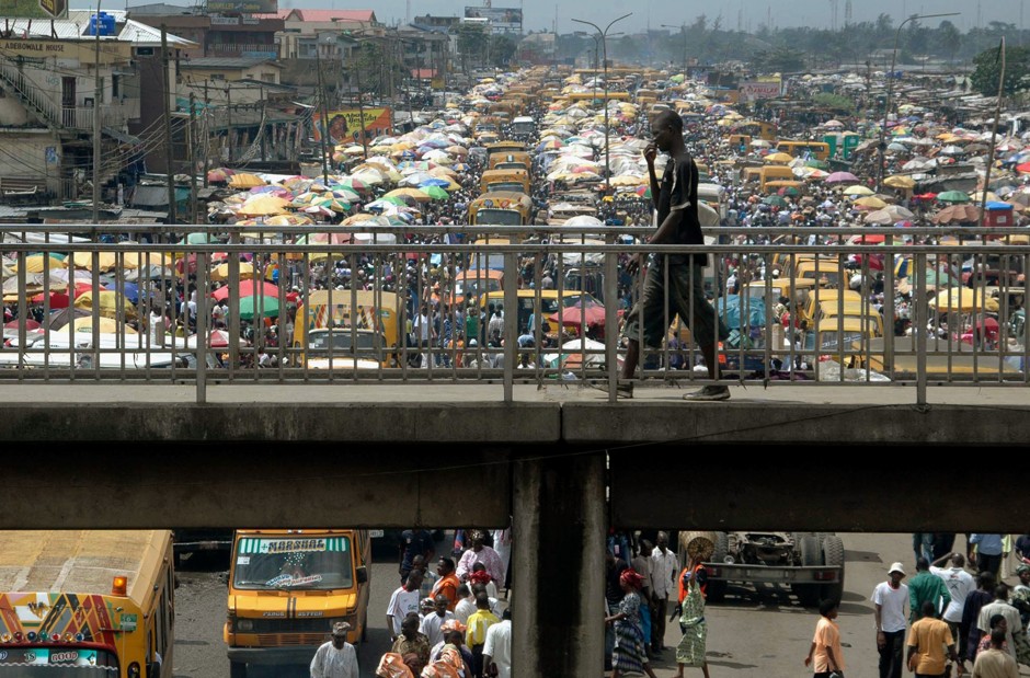 A man walks on a pedestrian bridge overlooking traffic in Lagos, Nigeria.