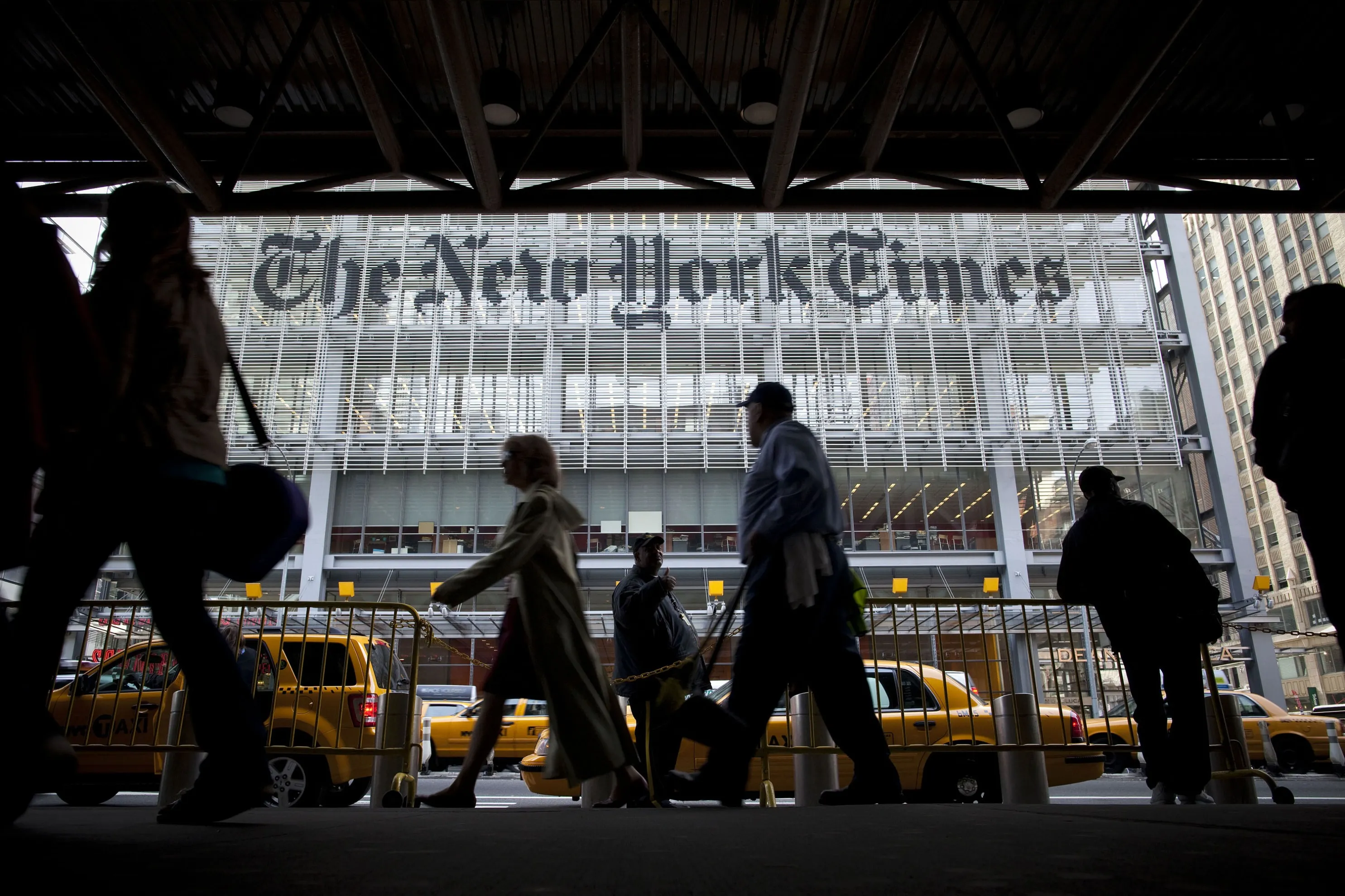 Pedestrians pass in front of the New York Times building.