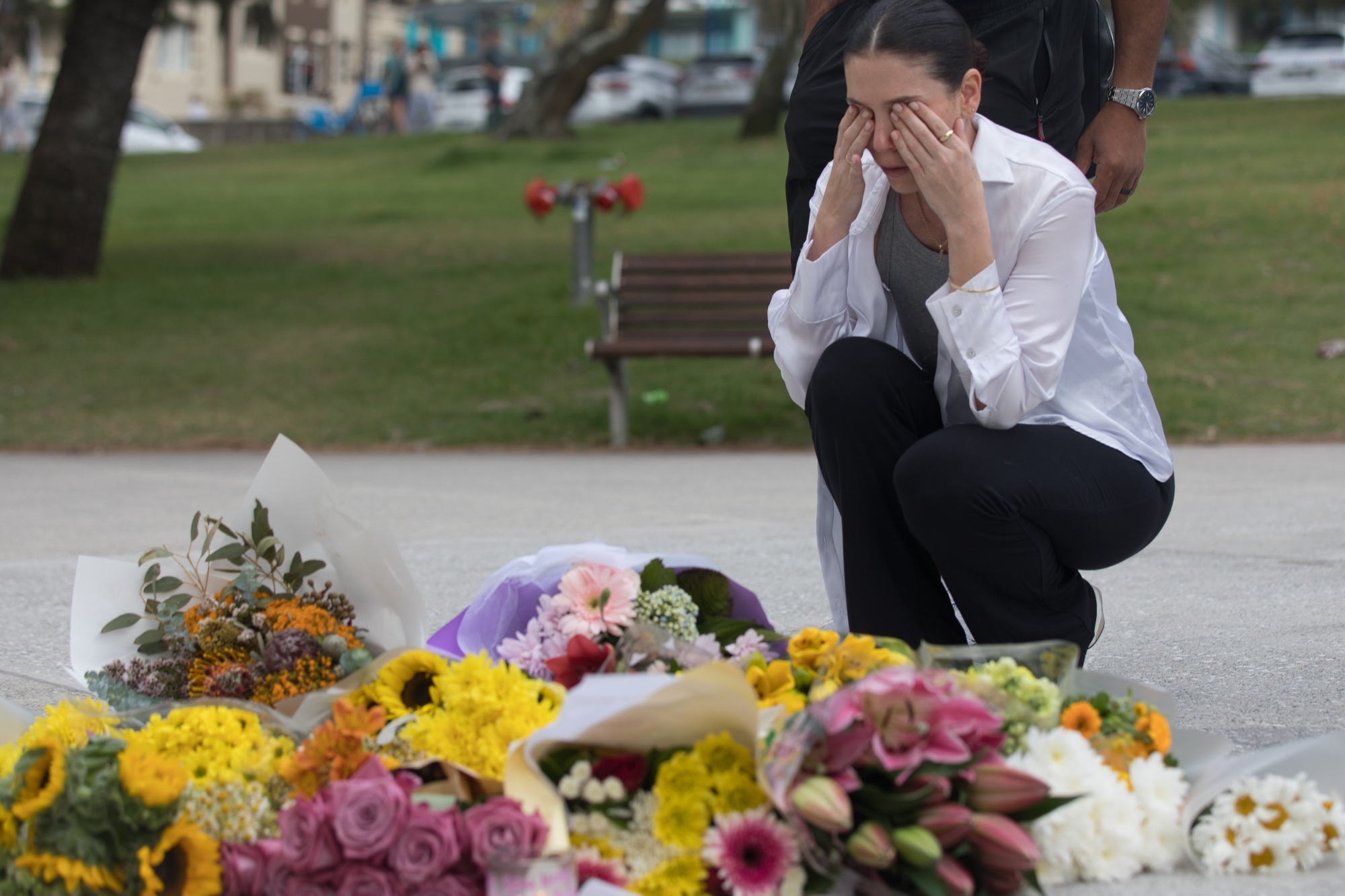 A mourner lays flowers near the scene of the mass shooting at Bondi Beach in Sydney, Australia, on Monday, Dec. 15, 2025. Sixteen people have been killed in Australia's worst terrorist attack after gunmen opened fire on Jewish people who had gathered to celebrate the first day of Hanukkah at Sydney's iconic Bondi Beach on Sunday evening. Photographer: Brent Lewin/Bloomberg