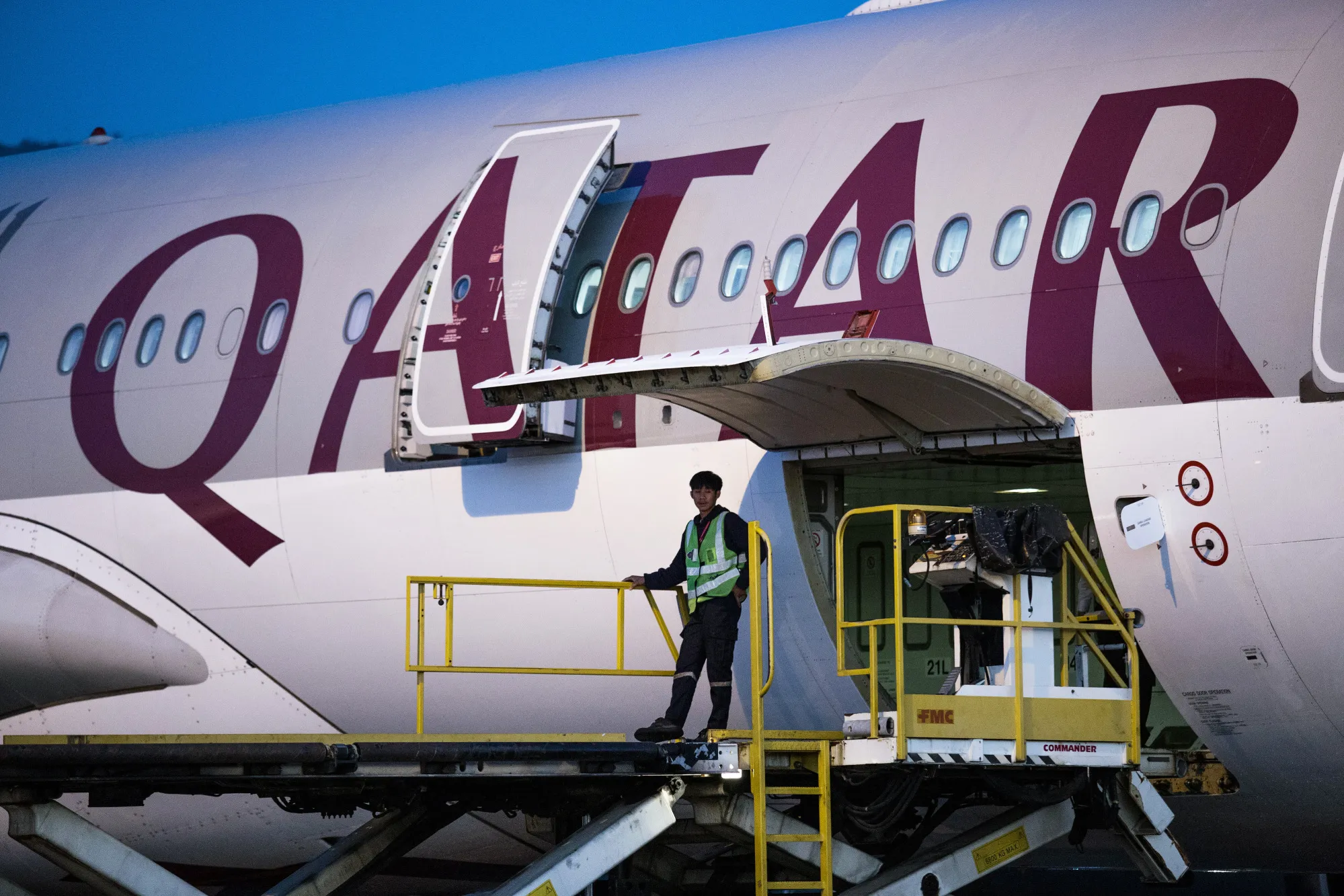 A member of ground staff stands on an elevated platform while unloading a Qatar Airways&nbsp;aircraft at Chiang Mai International Airport in Chiang Mai, Thailand.