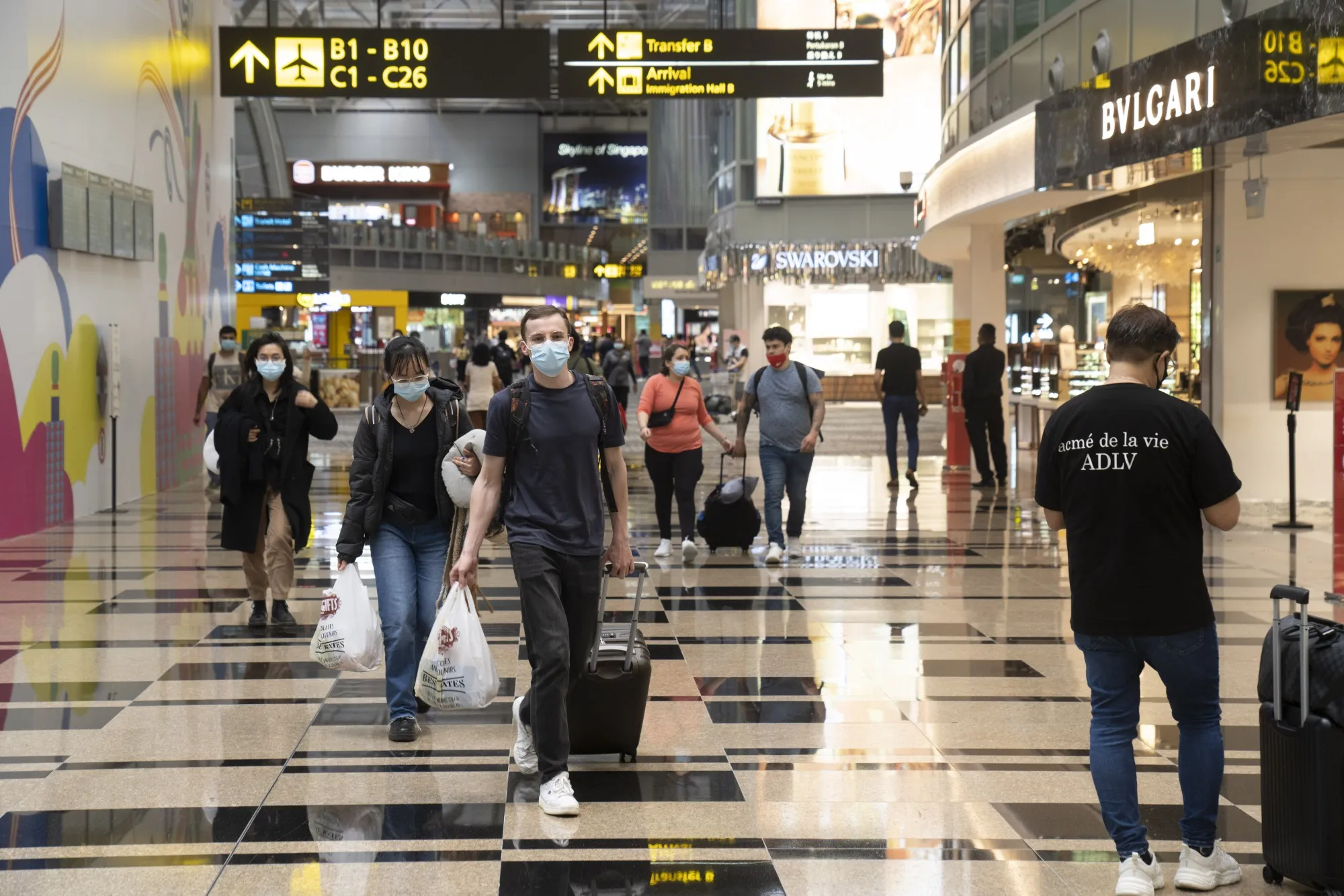 Travelers walk through the transit area at Singapore’s Changi Airport on March 30.