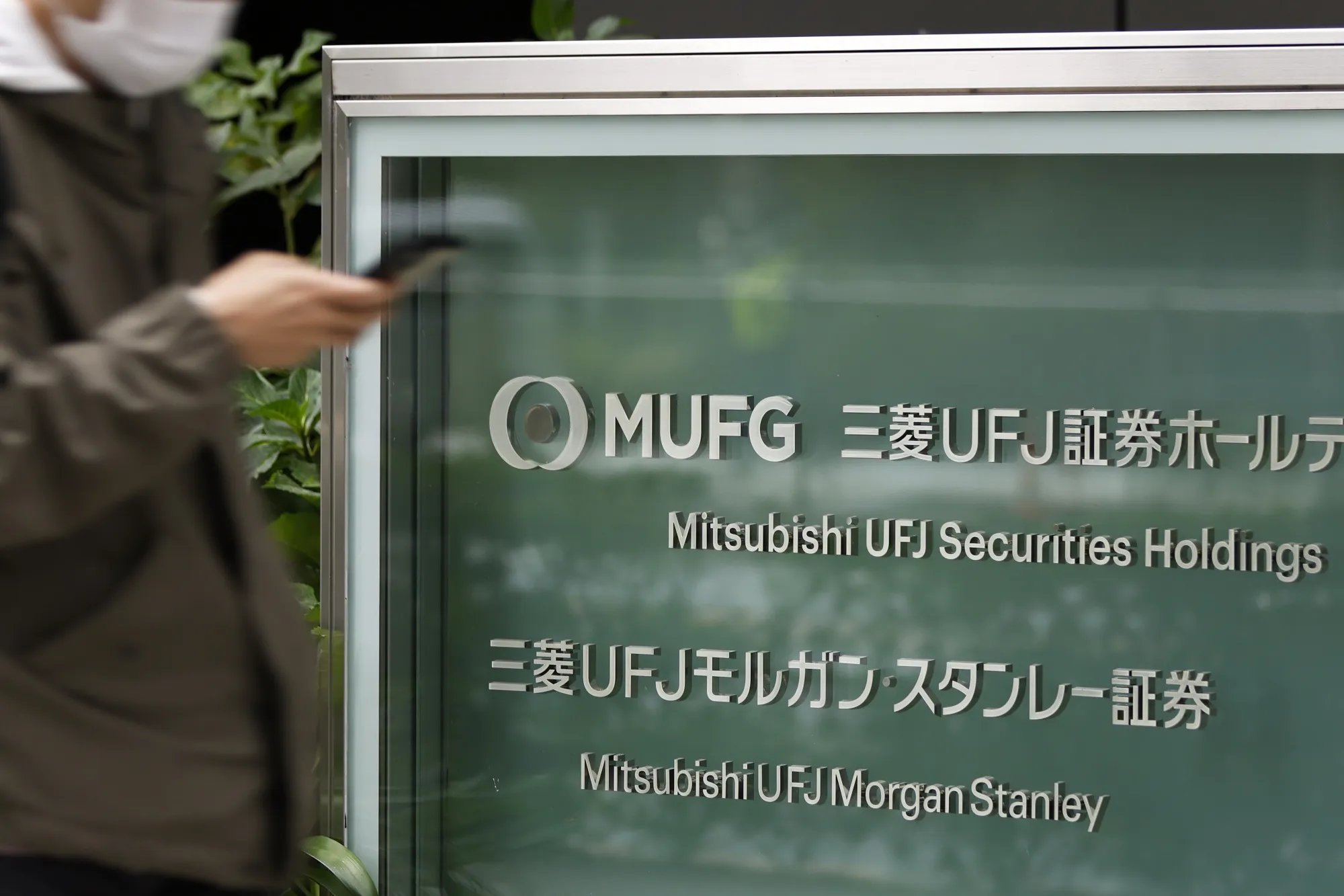 A pedestrian walks past signage for Mitsubishi UFJ Morgan Stanley Securities.
