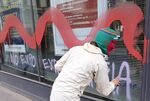 A demonstrator uses spray paint to write &quot;No Expo&quot; and &quot;Expo = Mafia&quot; on the front of a bank during a protest against Expo 2015 in Milan.