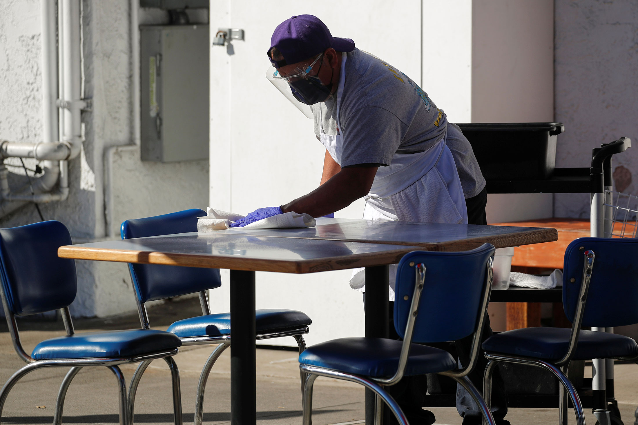 A worker cleans a sidewalk table outside Eat at Joe’s restaurant in Redondo Beach, Calif., on Nov. 30, 2020.