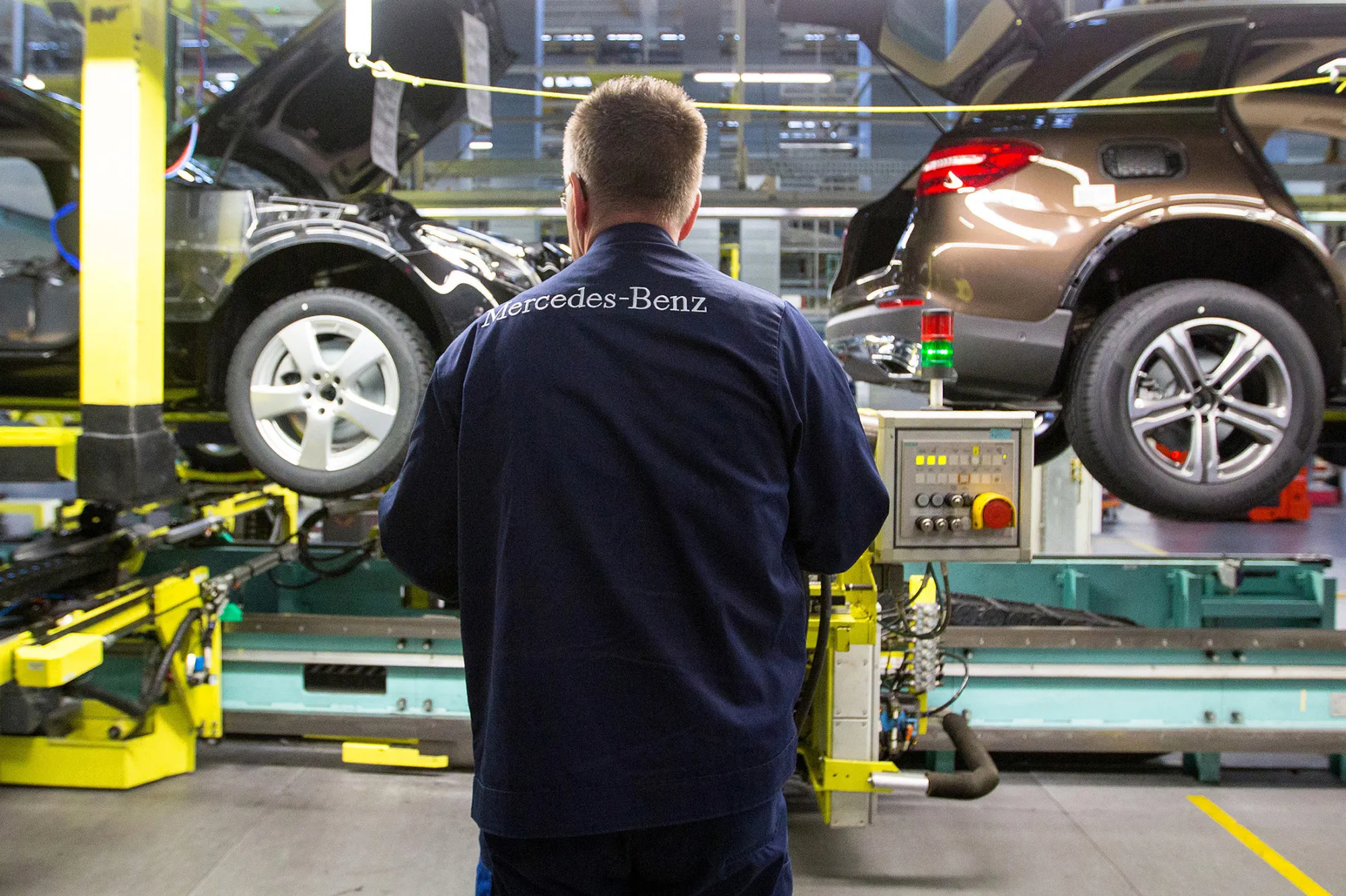 An employee stands beside Mercedes-Benz GLC sports utility vehicles (SUV) on the assembly line at the luxury automaker's factory in Bremen, Germany, on Tuesday, Jan. 24, 2017. BMW lost its crown as the world's biggest luxury-car brand to Mercedes-Benz, ending its reign after more than a decade amid a cluttered lineup of aging models.
