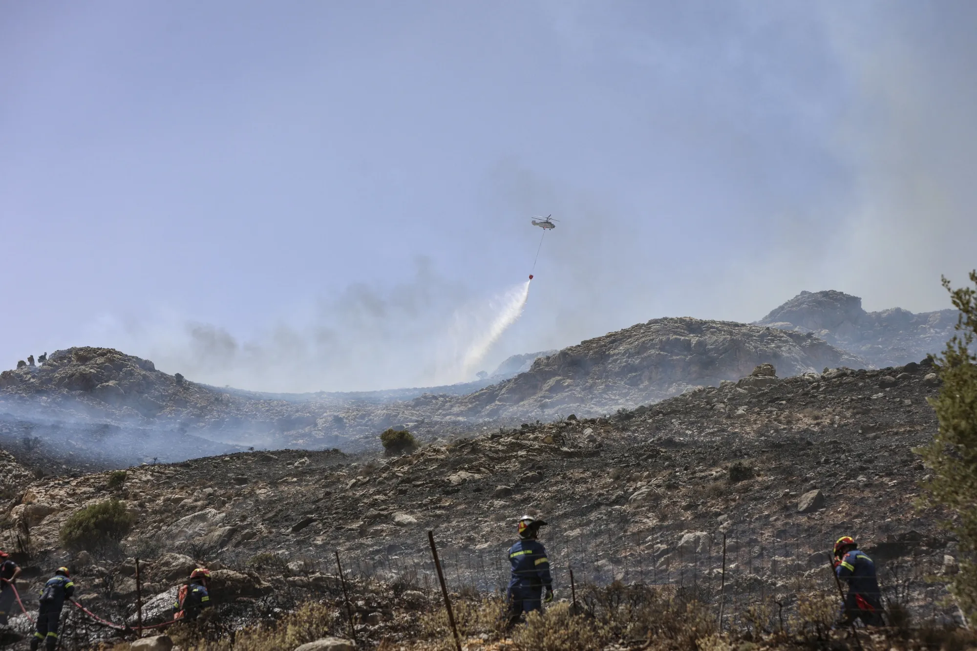 A helicopter dumps water over a wildfire near Akoumia in Crete, Greece, on June 26.