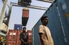 Drivers walk under a gantry crane as it moves a shipping container at the Jawaharlal Nehru Port, operated by Jawaharlal Nehru Port Trust (JNPT), in Navi Mumbai, Maharashtra, India, on Saturday, Dec. 16, 2017. Many of the cargo containers passing through India's busiest port in Mumbai have a small piece of Japan Inc. attached: Devices from NEC Corp. that can be tracked as the containers rumble through the interior of Asia's third-largest economy.