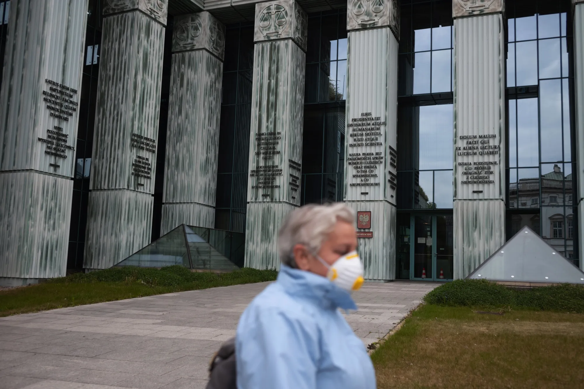 An elderly pedestrian wearing a protective face mask passes Poland's Supreme Court building in Warsaw.