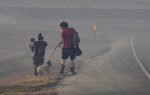 A family walks through smoke down the Arnold Blvd. frontage road after evacuating the Continental Villa mobile home park in Abilene, Texas on March 17, 2022.