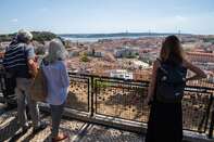 People look at the city of Lisbon from the viewpoint of