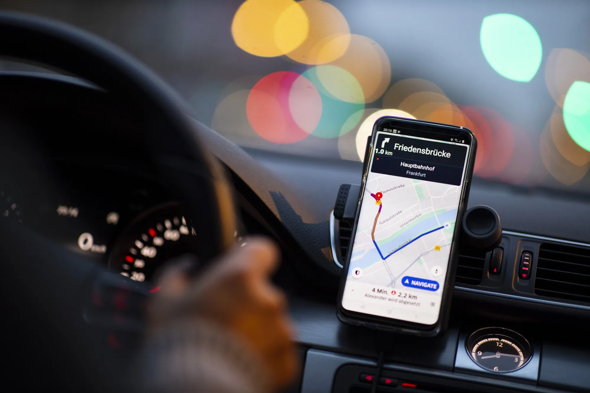 A dashboard-mounted smartphone displays the Uber app in Frankfurt, Germany.