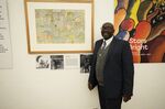 Gift Livingtsone Sango, 65, stands next to a painting by his father depicting Jesus as a Black man at the National Gallery of Zimbabwe, Thursday, July 14, 2022. The painting done by his late father in the 1940s is part of a historic exhibit, &quot;The Stars are Bright,&quot; now showing in Zimbabwe for the first time since the collection left the country more than 70 years ago. A photograph of Sango's father, Livingstone, as a young boy hangs next to the painting. (AP Photo/Tsvangirayi Mukwazhi)