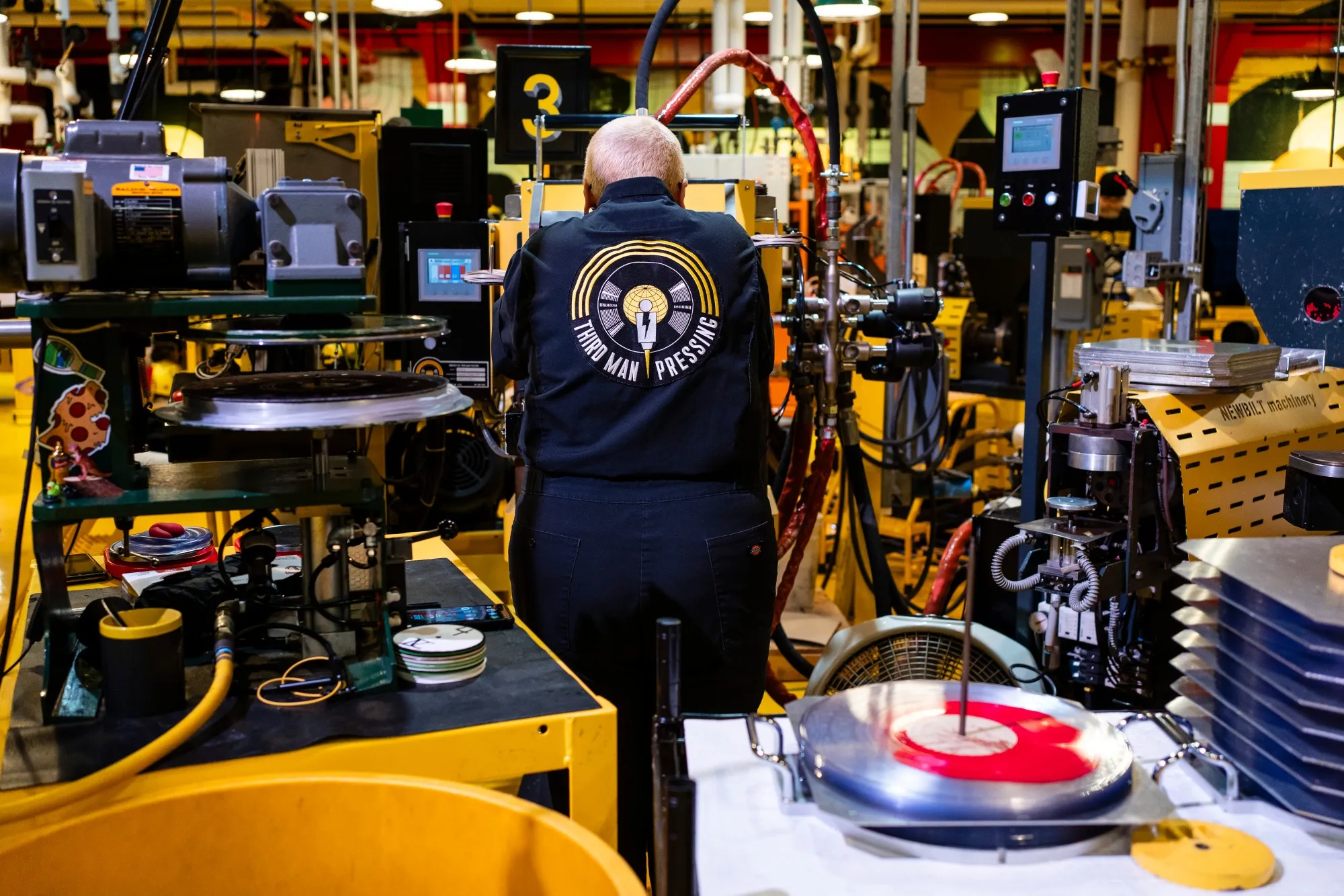 A worker removes a vinyl record from a press at the Third Man Pressing manufacturing facility in Detroit