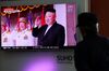 A man watches a television screen showing an image of Kim Jong Un,.