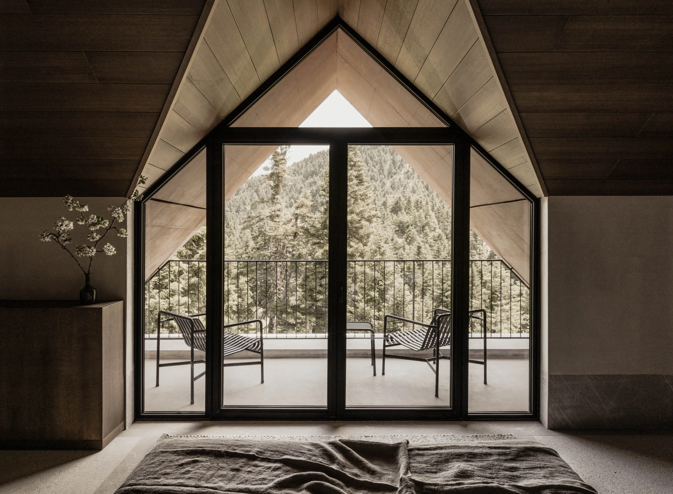 A room with geometric floor-to-ceiling windows — and views of the Peloponnese mountains — at Manna Hotel in Arcadia, Greece.