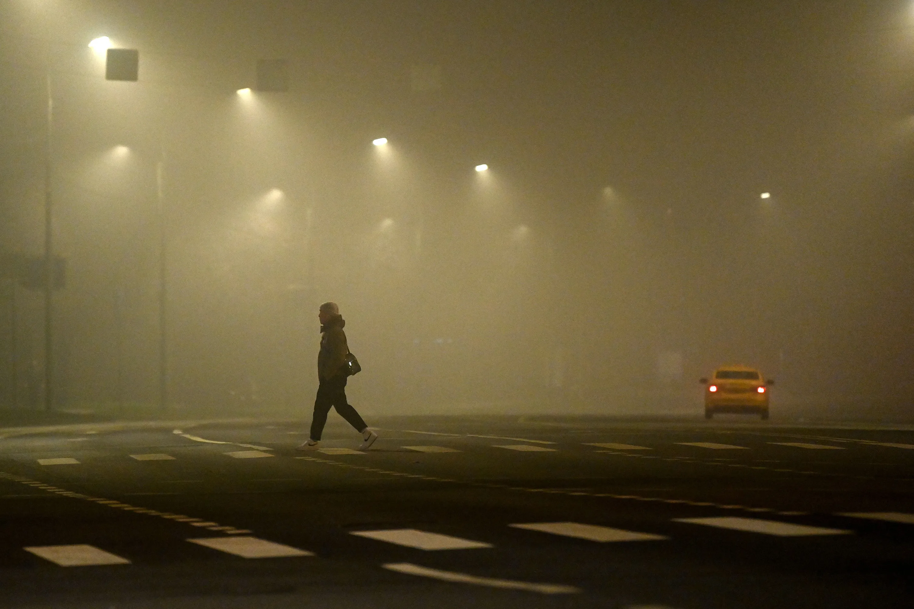 A man crosses a street during a heavy fog in Moscow late on Nov. 1.