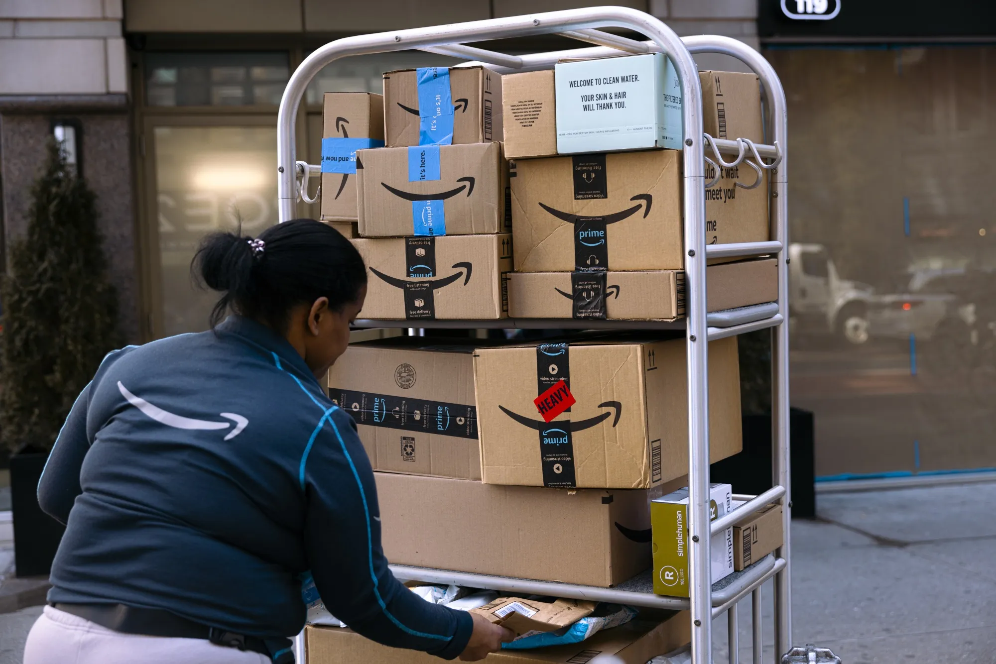 An Amazon worker stacks packages onto a luggage cart outside an apartment building in New York.