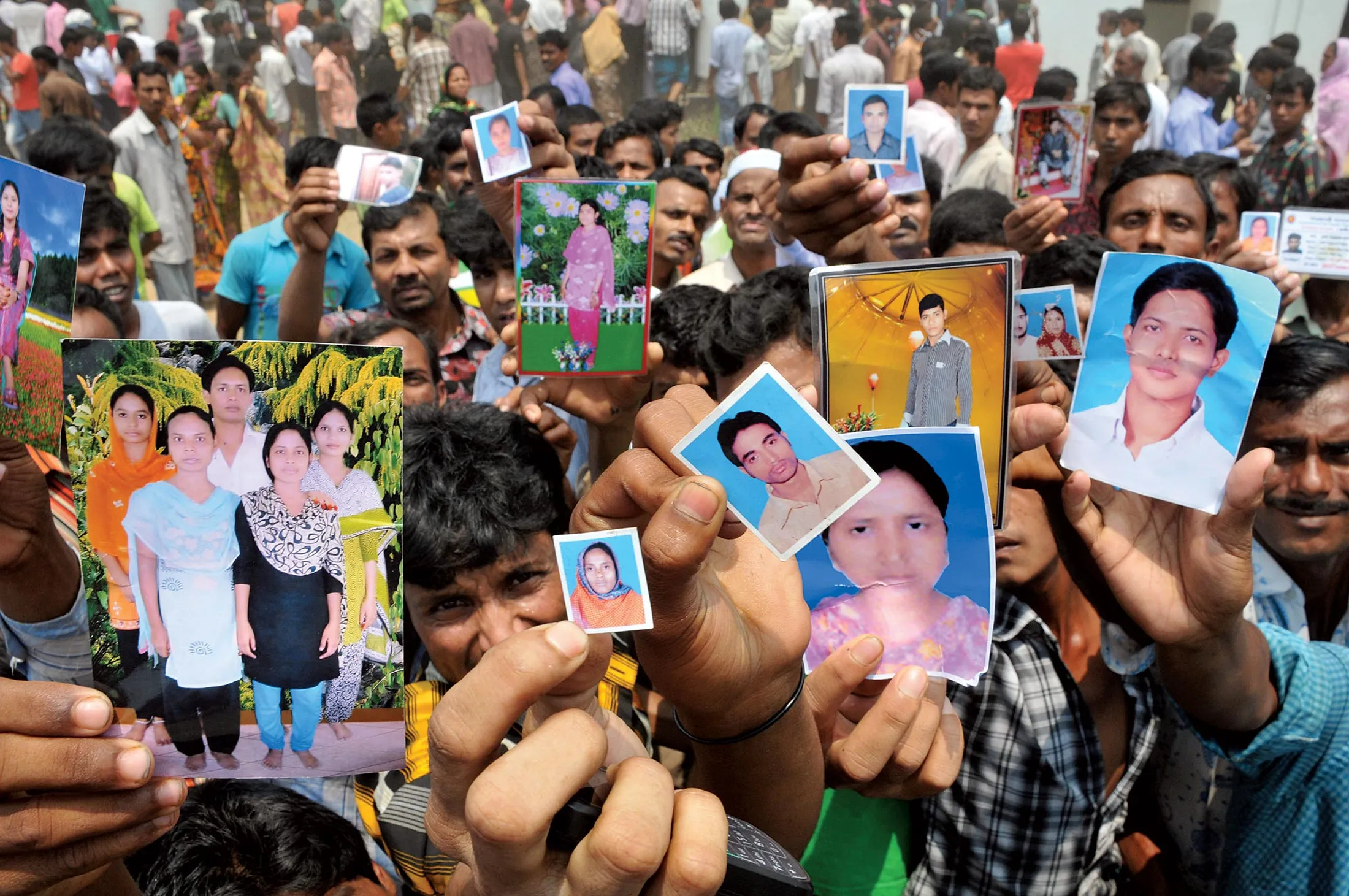 Relatives hold photos of workers missing in the Rana Plaza collapse.
