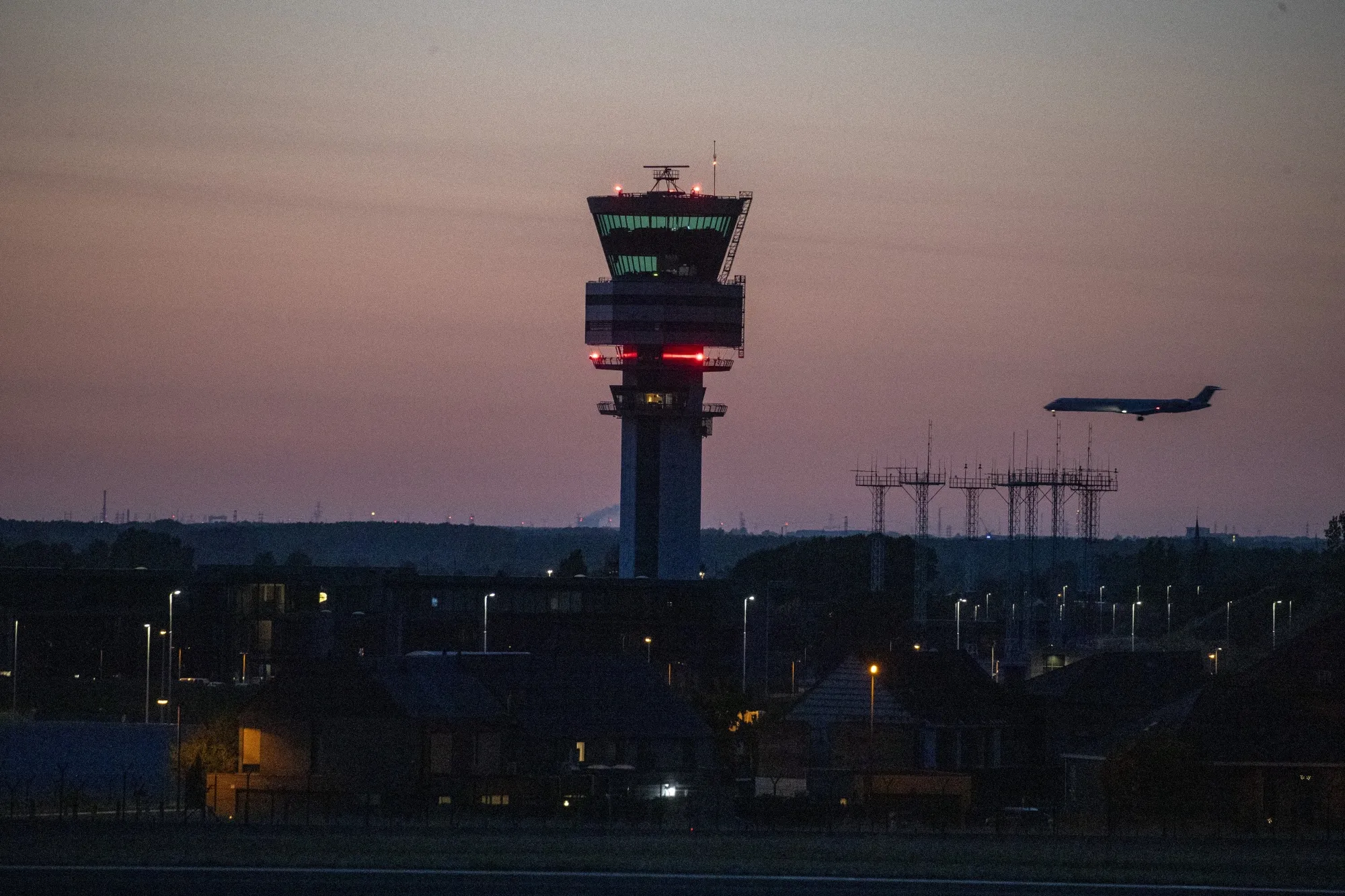 An aircraft flying past the control tower as it lands at Brussels Airport by night.
Photographer: Nicolas Maeterlinck/AFP/Getty Images