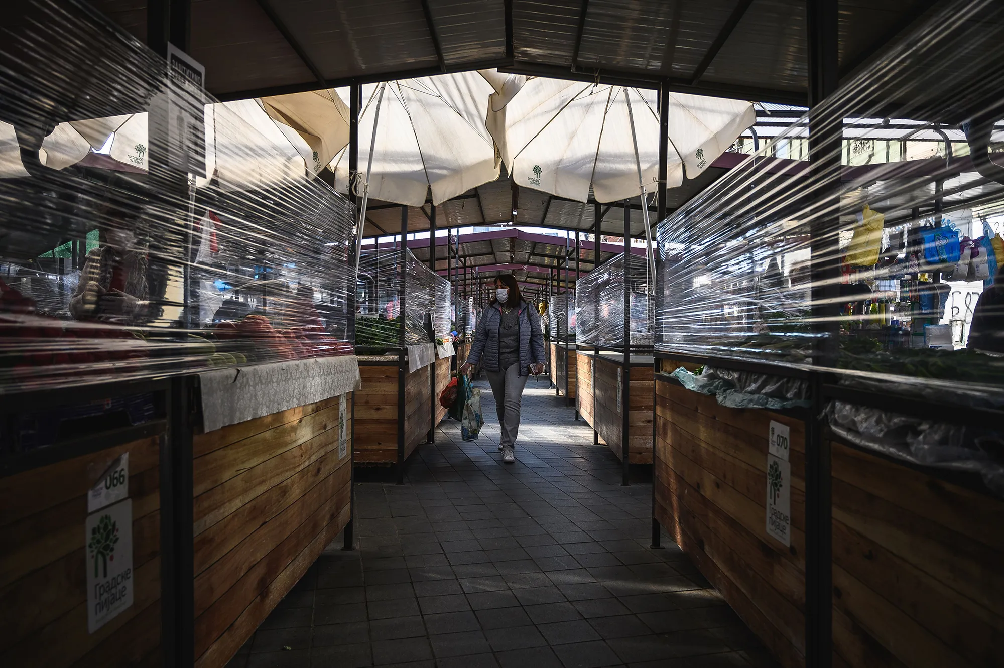 A customer looks at vegetables displayed behind a cling film protective wrap at a farmers market in Belgrade on April 23.&nbsp;