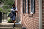 A United States Postal Service&nbsp;letter carrier wears a protective mask while delivering mail in Fairfax, Virginia on May 19.