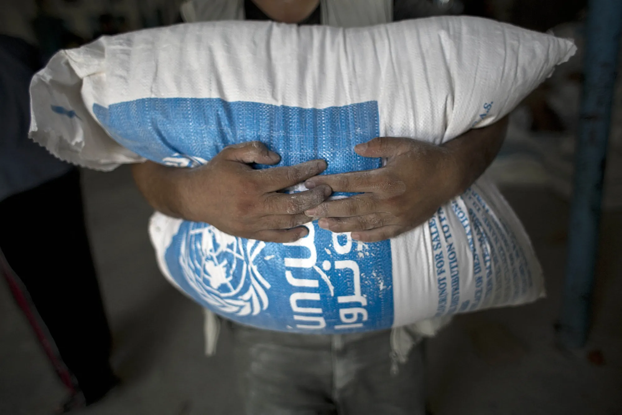 A Palestinian resident carries a bag of wheat flour distributed at a United Nations Relief and Works Agency center in Rafah, Gaza.&nbsp;