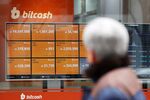 A pedestrian looks at a monitor showing the prices of virtual currencies at the Bithumb exchange office in Seoul, South Korea.