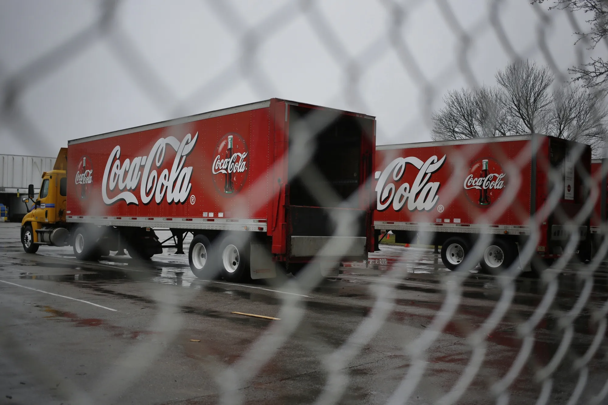 Delivery trucks sit parked outside a Coca-Cola Co. bottling plant.