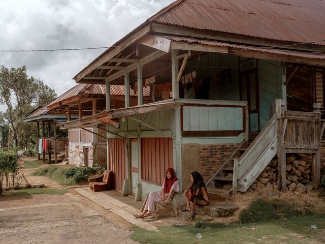 wo villagers sit in front of a traditional house in Ngarip.