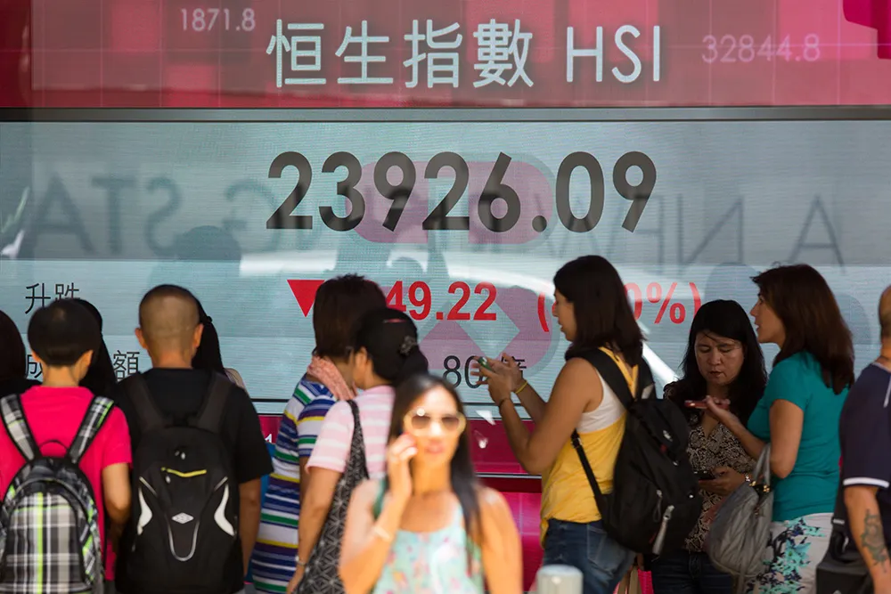 Pedestrians walk past an electronic display showing the Hang Seng Index figure in Hong Kong, China.
