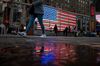 Pedestrians walk past an illuminated American flag in the Times Square area of New York