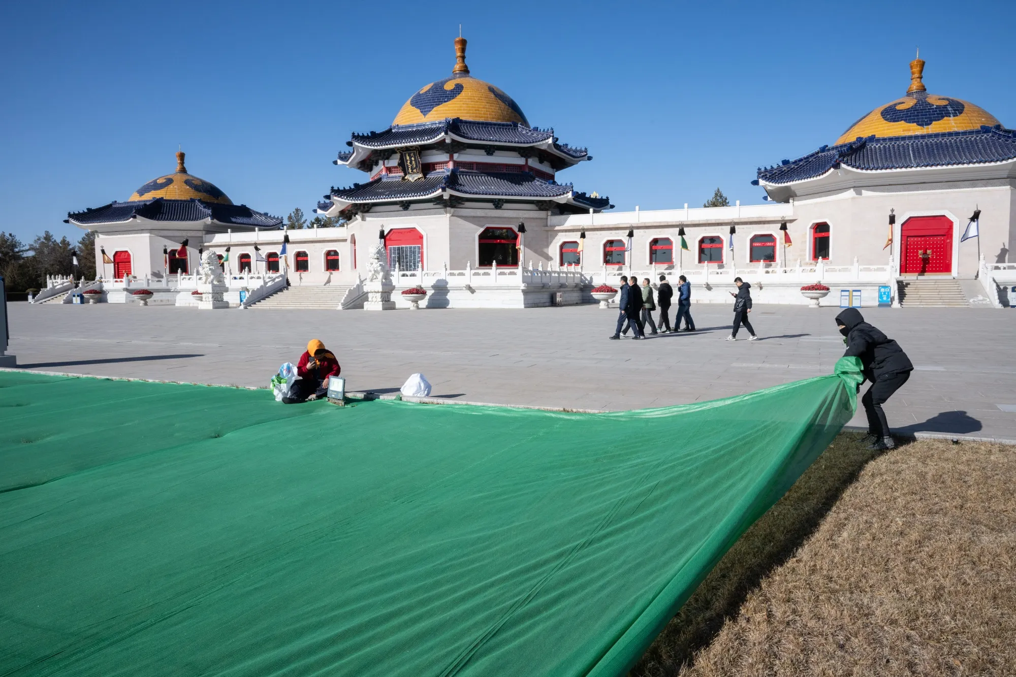 Workers puts a cover on the grass for protection at Genghis Khan Mausoleum in Ordos, Inner Mongolia, China.