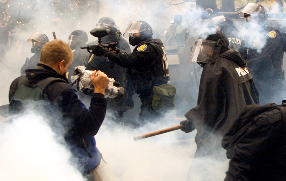 Seattle police fire teargas as protesters run outside the site of the World Trade Organization conference on November 30, 1999.