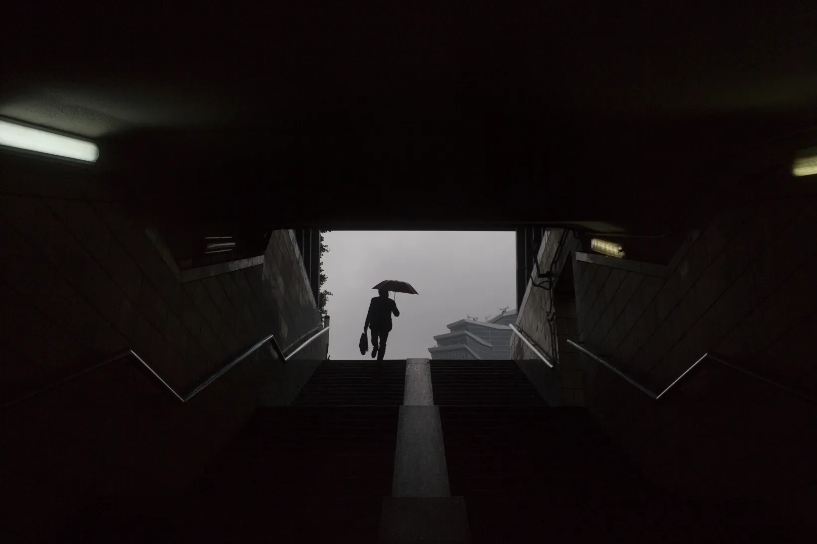A man holding an umbrella exits a pedestrian tunnel in the Luohu district of Shenzhen, China, on Tuesday, Dec. 17, 2013. Data on home prices and foreign direct investment showed gains last month.