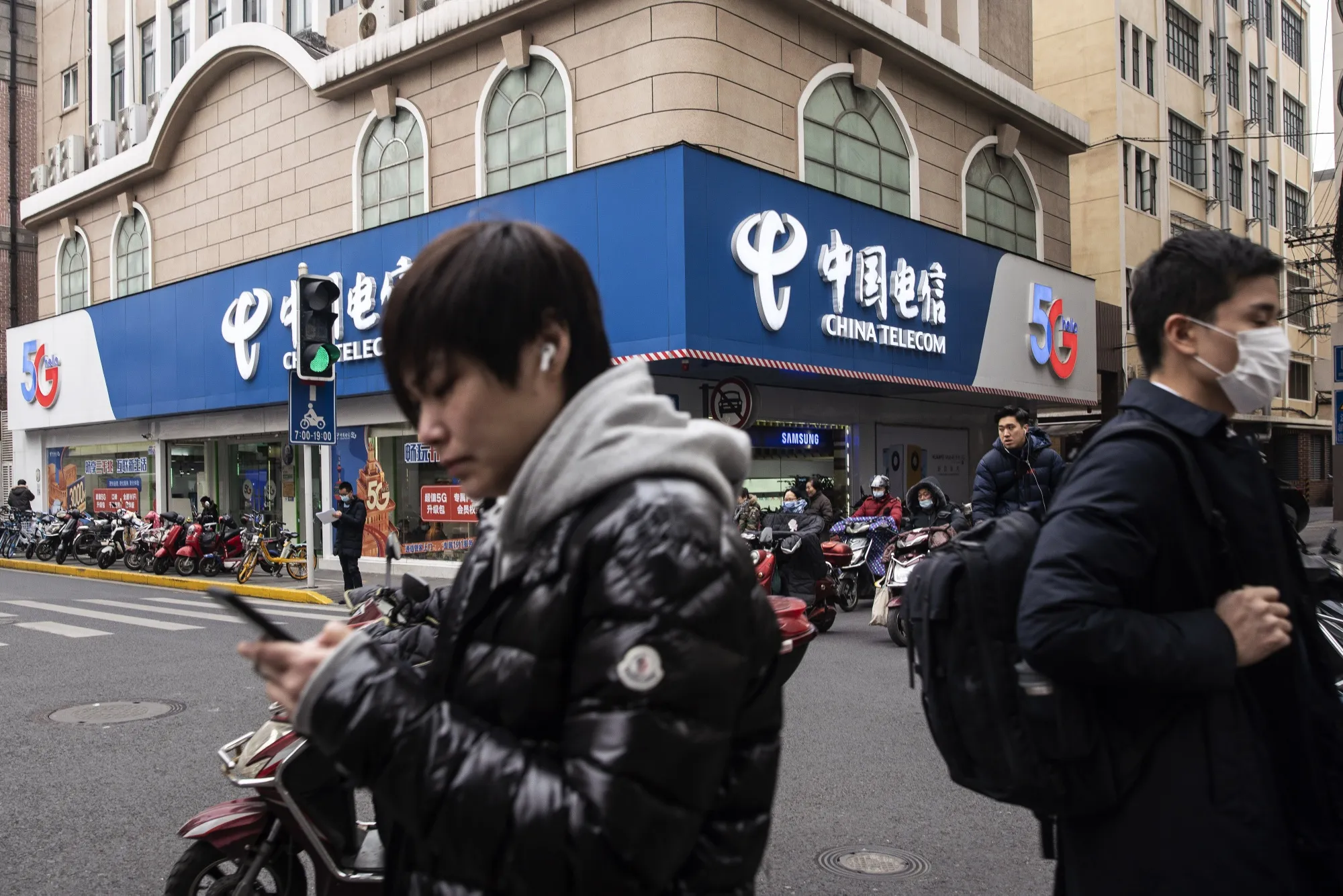 Pedestrians walk past a China Telecom Corp. store in Shanghai.