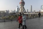 Pedestrians wearing protective masks walk on a footbridge in the Lujiazui Financial District in Shanghai, China, on Thursday, Jan. 30, 2020.