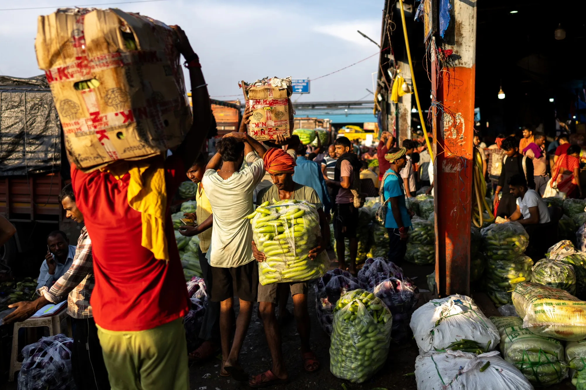 Workers carry sacks of vegetables at a wholesale market in New Delhi, India.