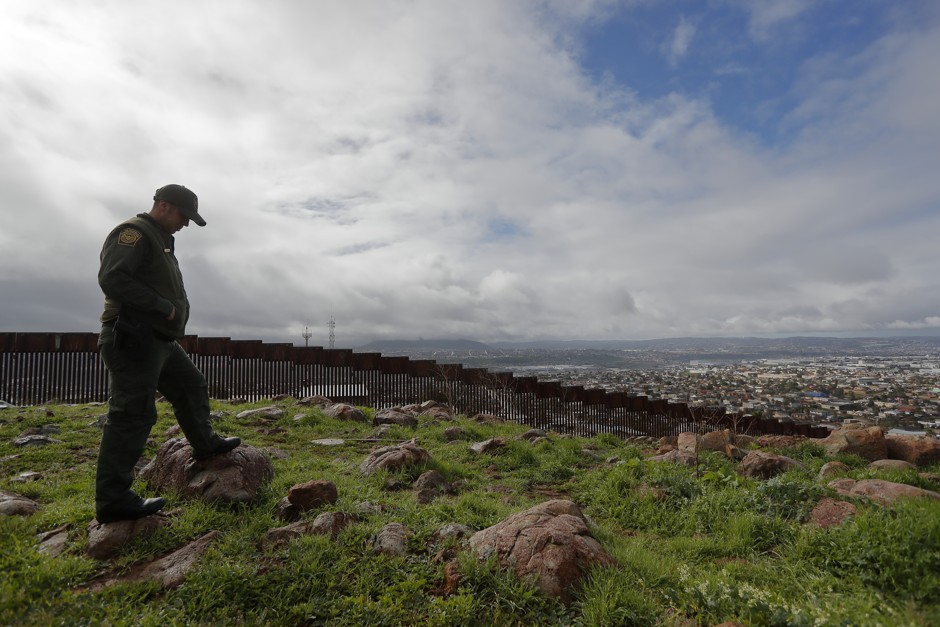 A Border Patrol agent looks on near a border wall that separates the cities of Tijuana, Mexico, and San Diego, California.