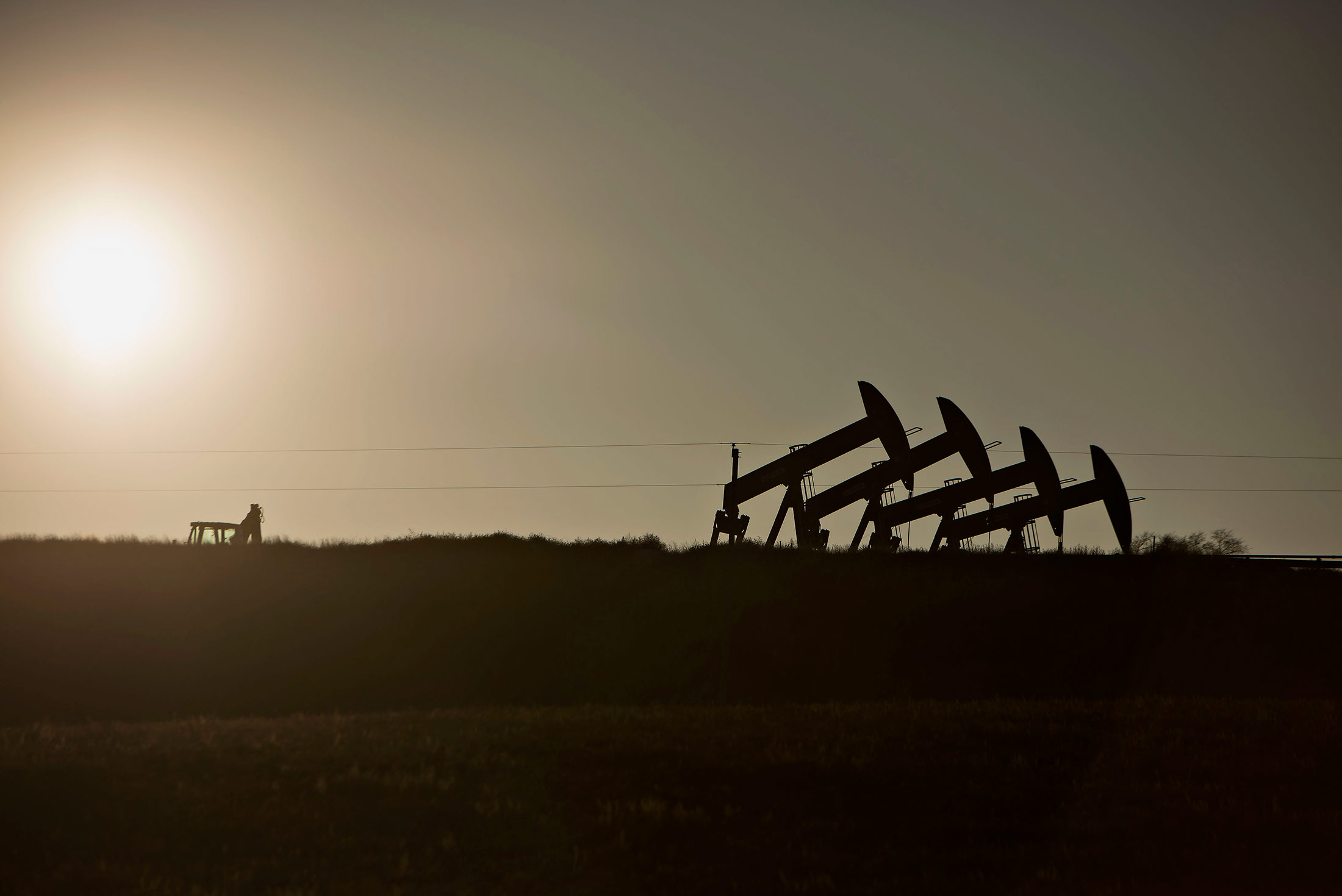 Four pumpjacks are silhouetted as they operate at the site of an oil well outside Williston, North Dakota, U.S., on Thursday, Feb. 12, 2015.
