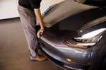 An employee closes the front hood of a Tesla Inc. Model 3 electric vehicle.