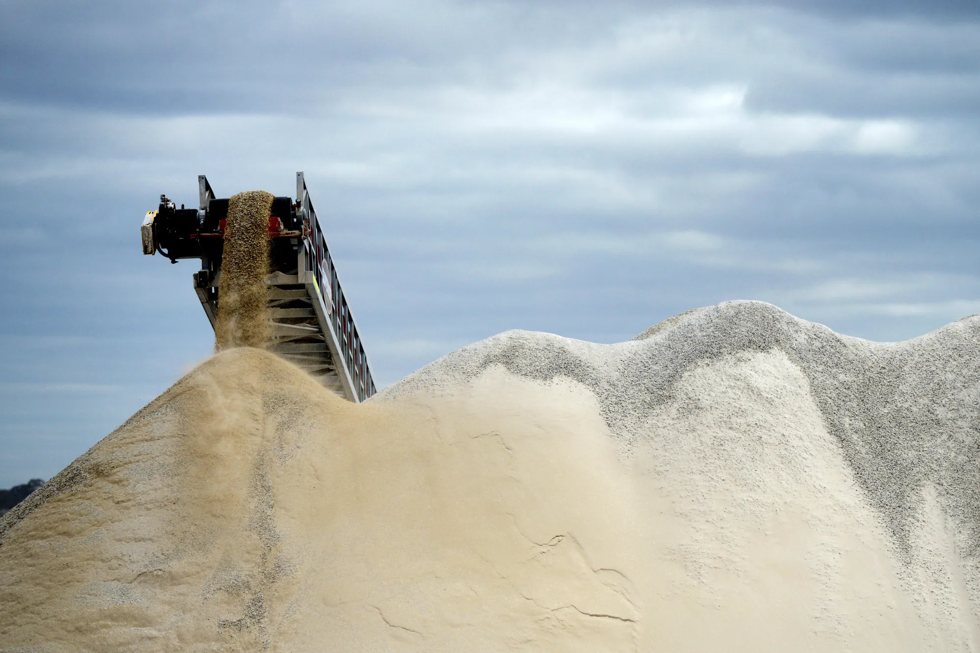 Lithium ore falls from a chute at a mine site.