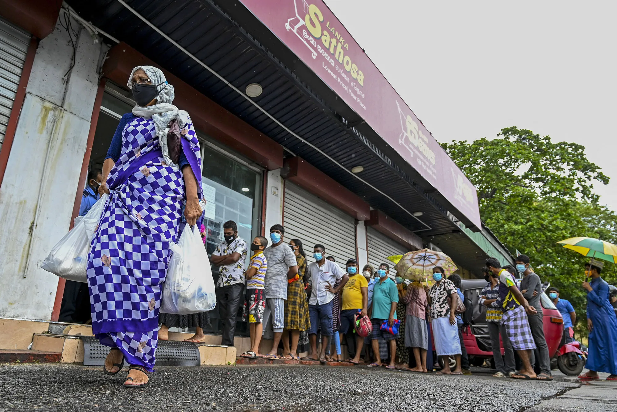 People queue outside a state-run supermarket to buy essential food items in Colombo, Sept. 3