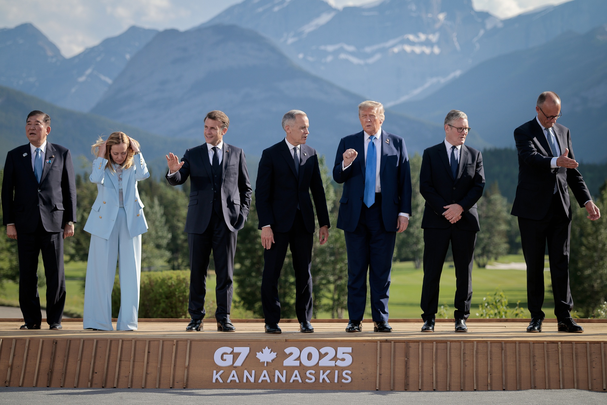 The leaders of the G7 stand assembled on a stage, with mountains in the background.