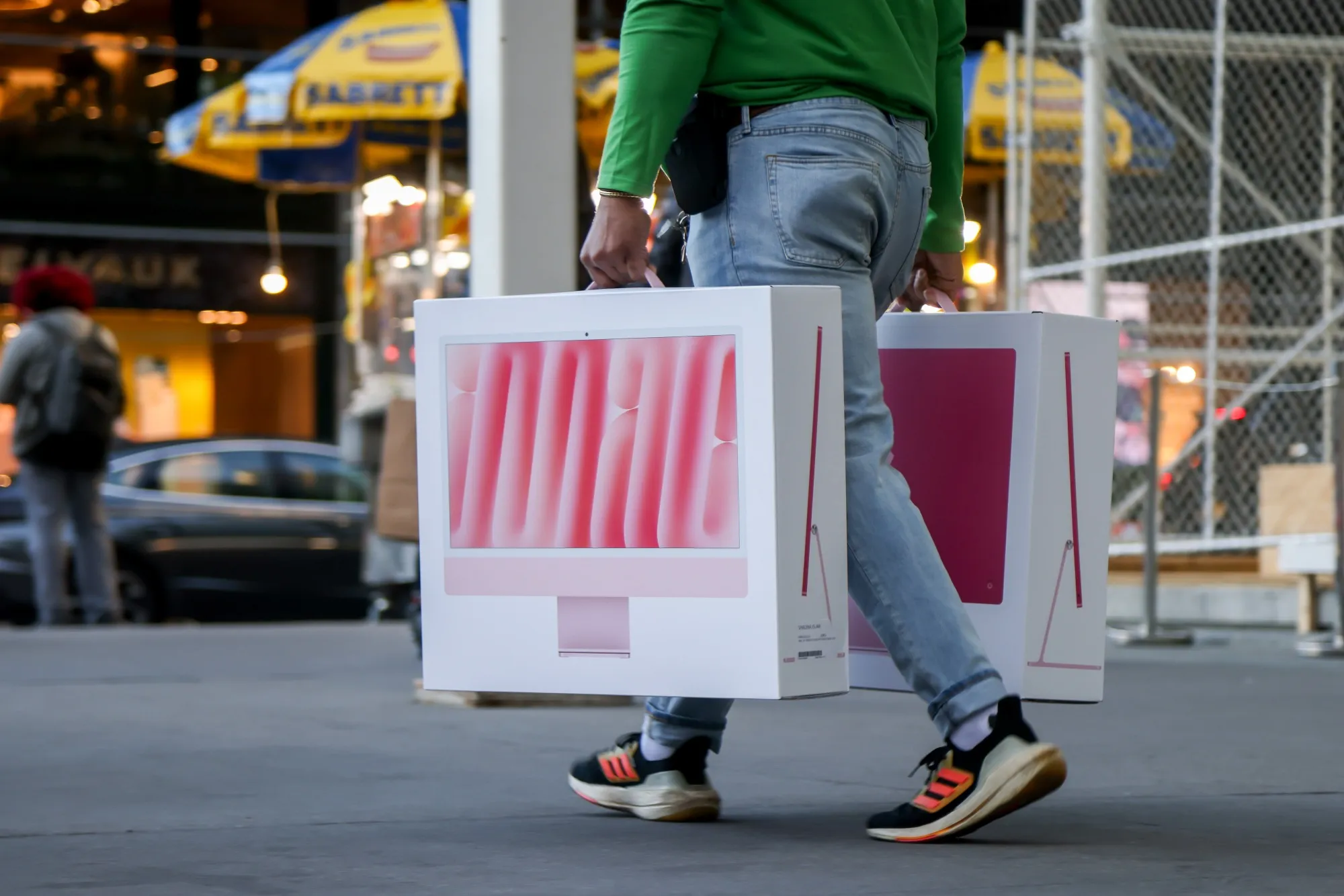 A shopper carries Apple iMac computers outside the company's Fifth Avenue store in New York.