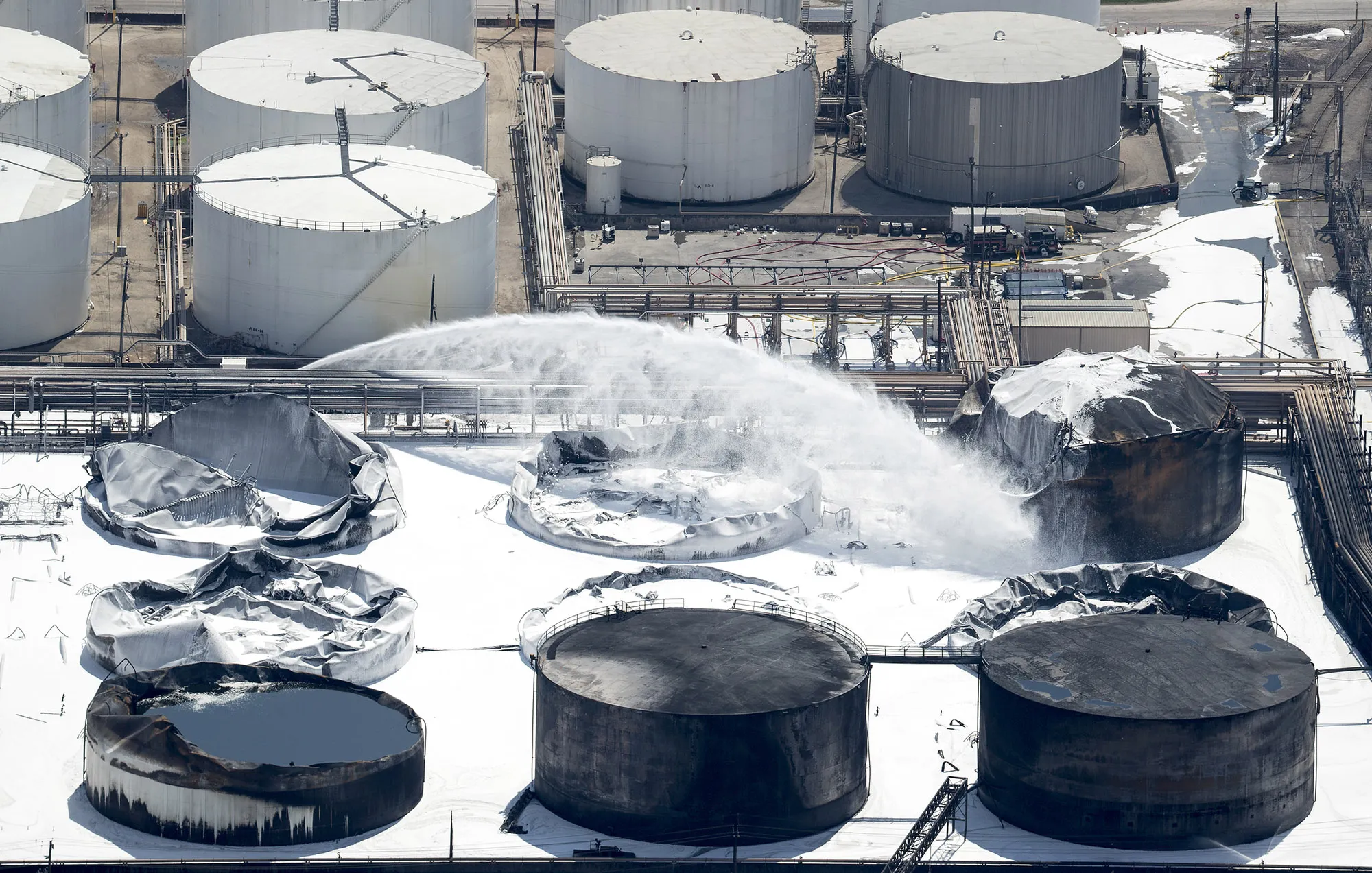 Emergency crews continue to douse what’s left of the now-extinguished petrochemical tank fire on March 20.